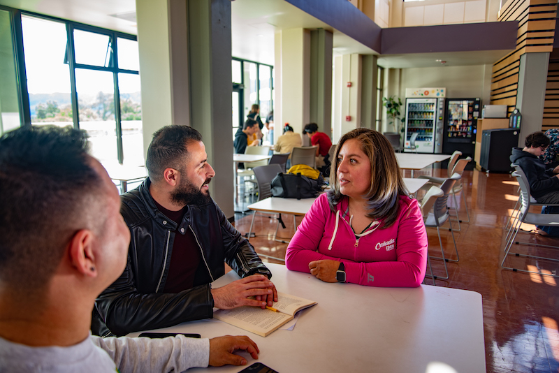 Adult students seating and takling at a table in The Grove in Building 5